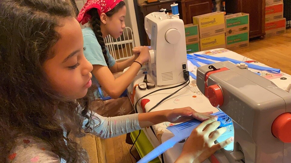 Young volunteer sewing fabric at a sewing machine
